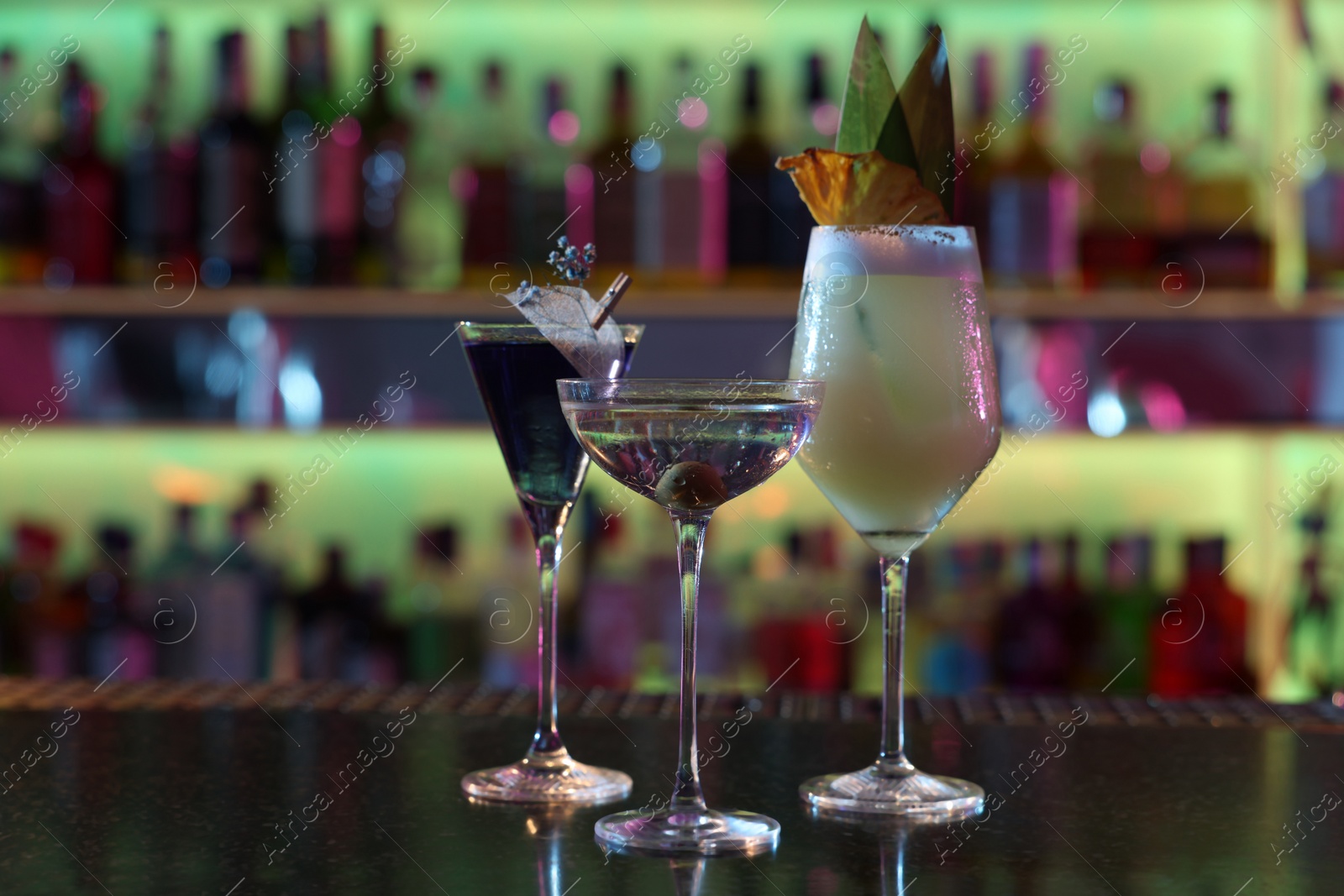 Photo of Different fresh alcoholic cocktails on counter in bar