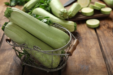 Photo of Zucchinis with parsley in basket on wooden table