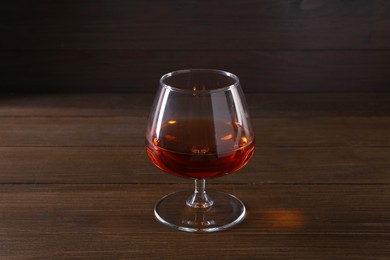 Delicious liqueur in glass on wooden table