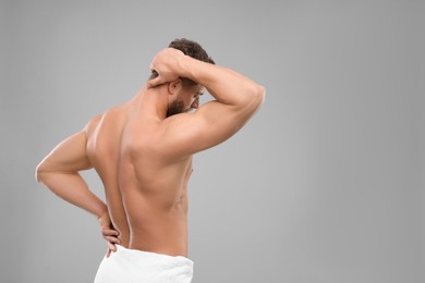 Man suffering from back pain on grey background. Space for text