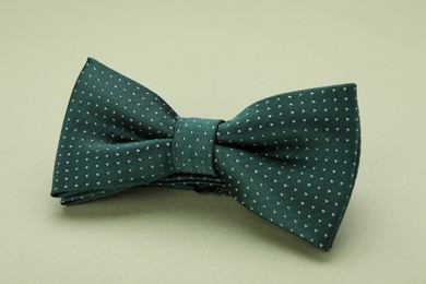 Photo of Stylish bow tie with polka dot pattern on pale green background, closeup