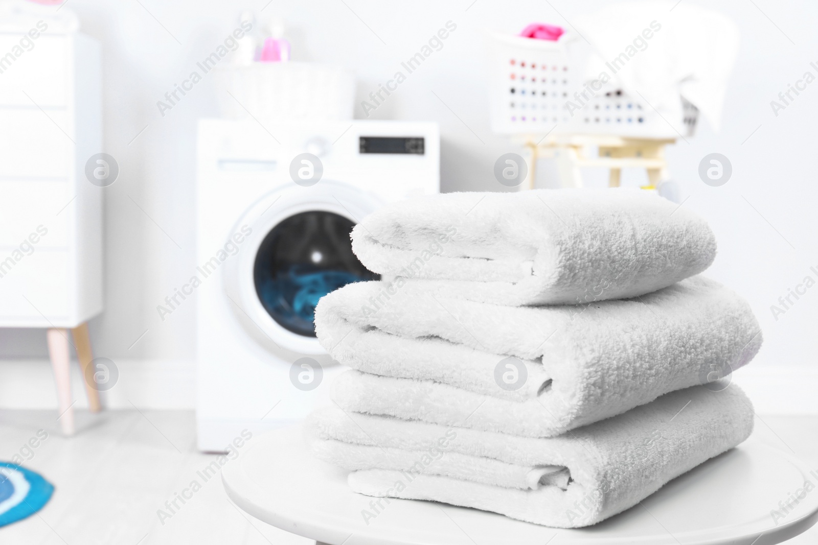 Photo of Stack of clean towels on table in laundry room. Space for text