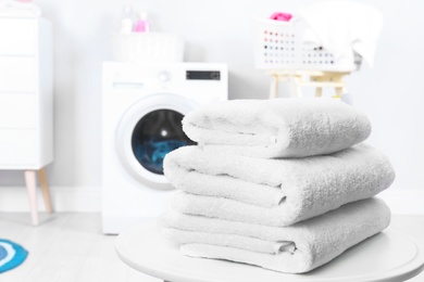 Stack of clean towels on table in laundry room. Space for text