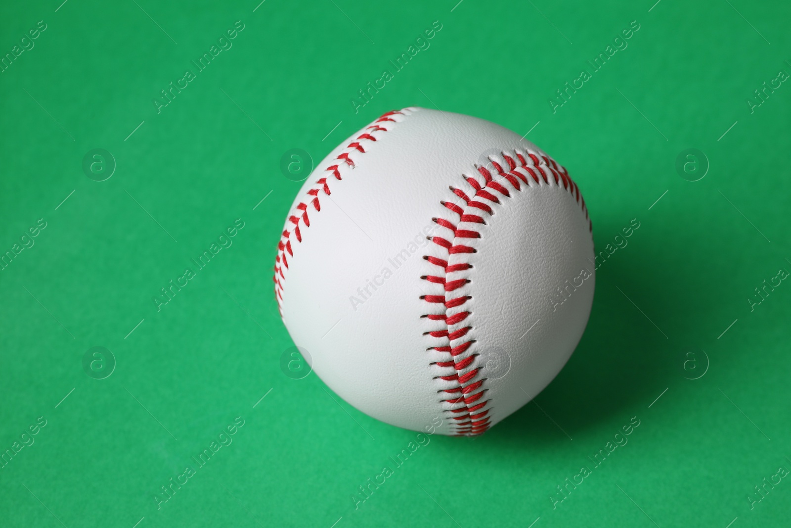 Photo of One baseball ball with stitches on green background