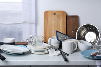 Many dirty utensils and dishware on countertop in messy kitchen