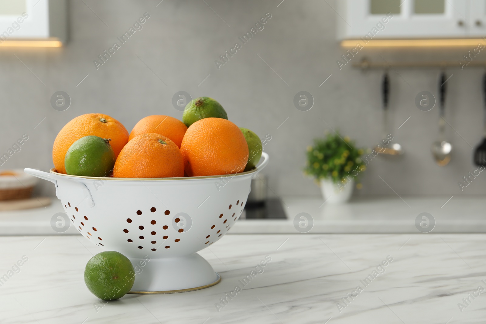 Photo of Colander with fresh fruits on white marble table in kitchen. Space for text