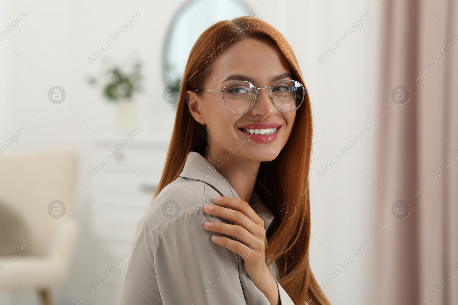 Photo of Portrait of beautiful young woman with red hair at home. Attractive lady smiling and looking into camera