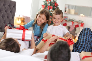 Happy parents and children with gifts celebrating Christmas at home