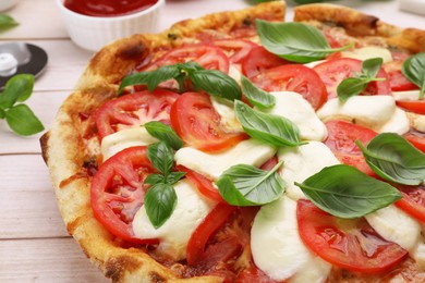 Photo of Delicious Caprese pizza with tomatoes, mozzarella and basil on light wooden table, closeup