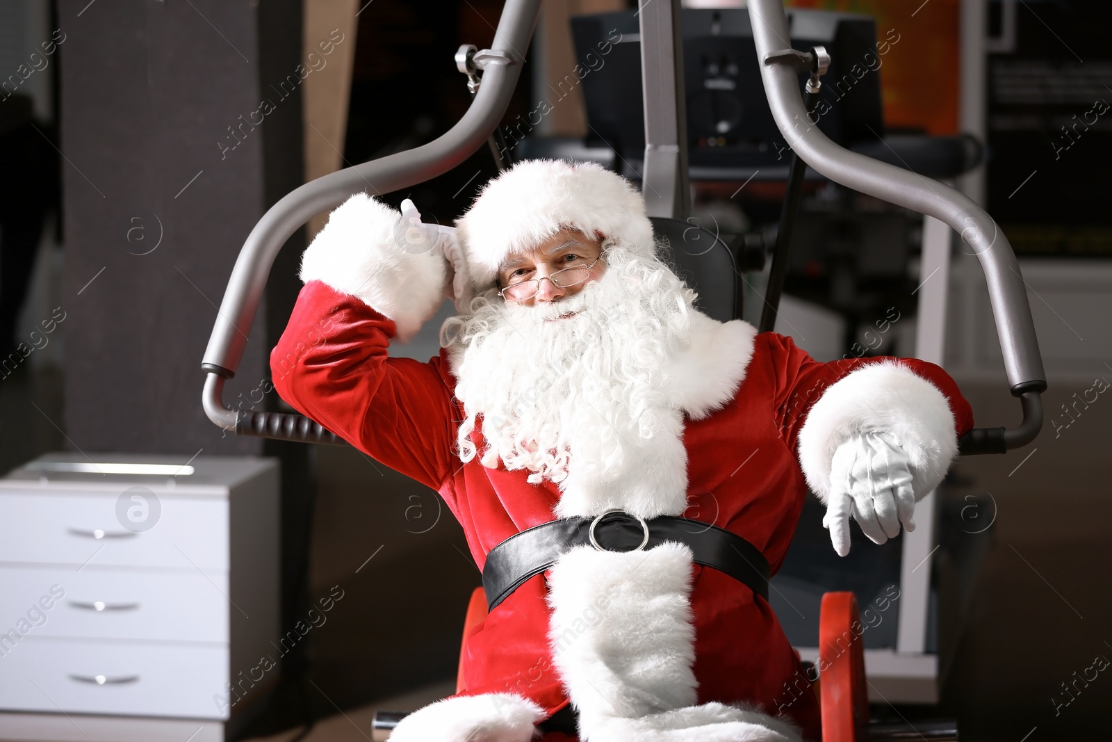 Photo of Authentic Santa Claus resting after exercise in modern gym