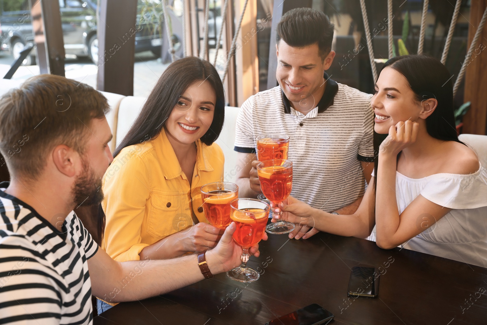 Photo of Friends with Aperol spritz cocktails resting together at restaurant