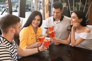 Photo of Friends with Aperol spritz cocktails resting together at restaurant