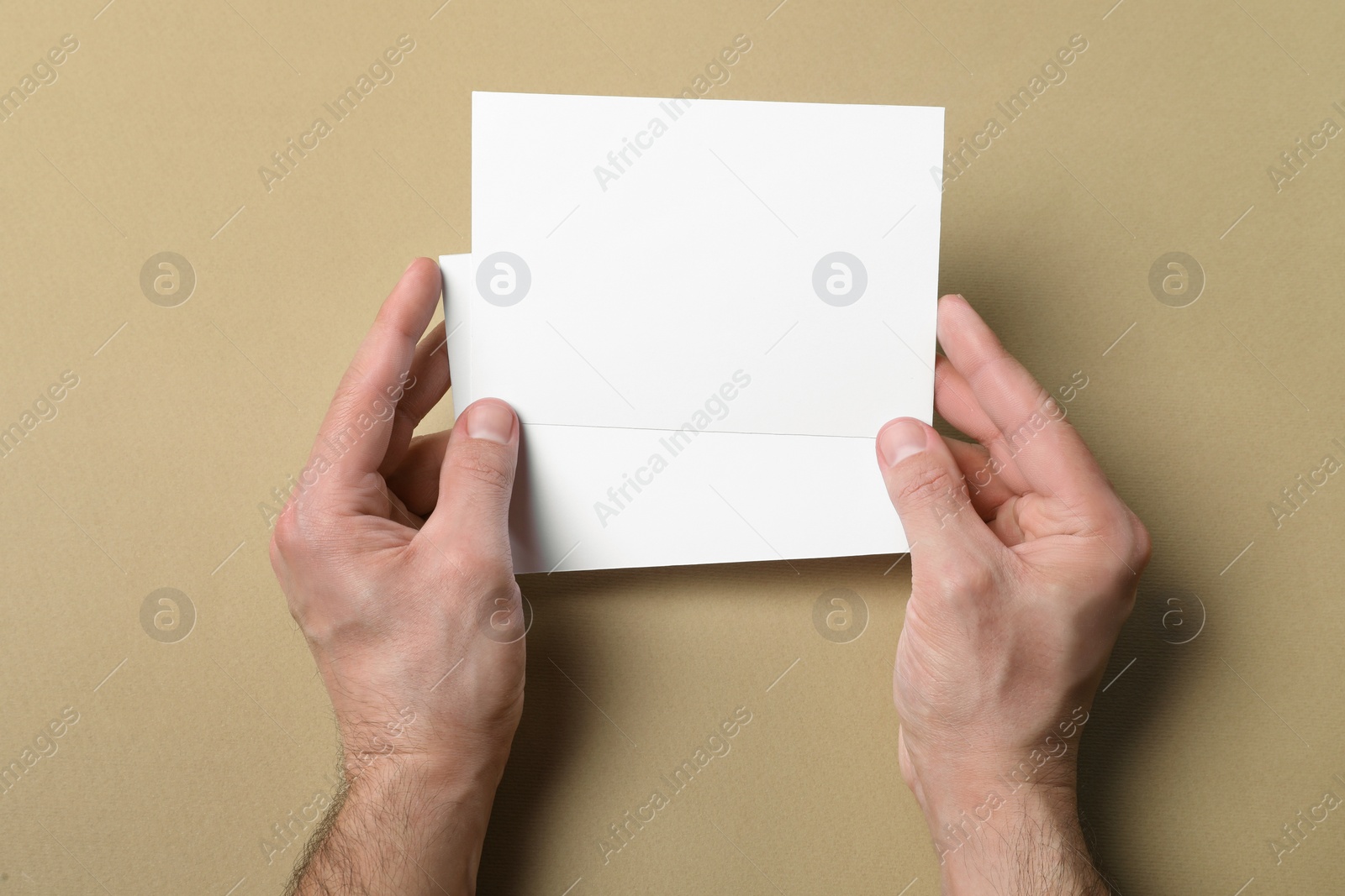 Photo of Man holding flyers on light brown background, top view. Mockup for design