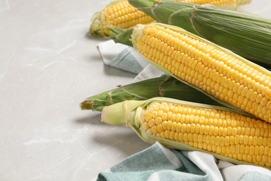 Bunch of corn cobs on light marble table, closeup