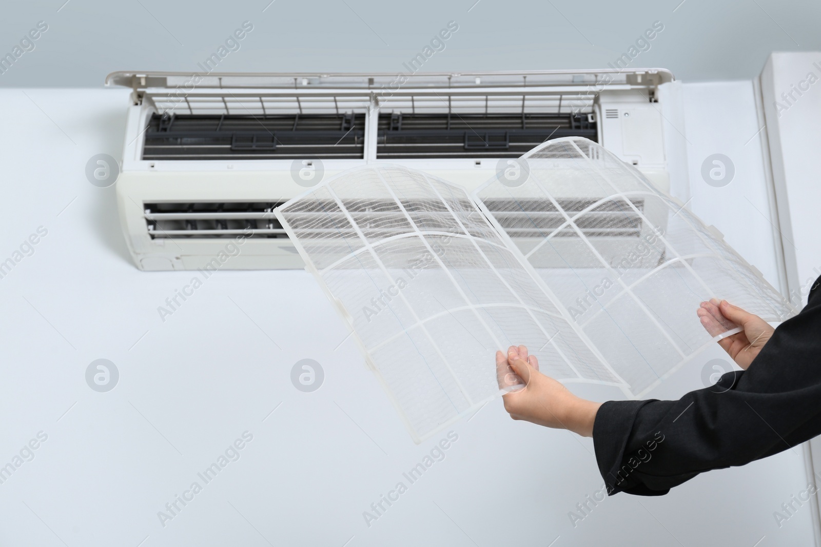 Photo of Woman holding air conditioner filters indoors, closeup