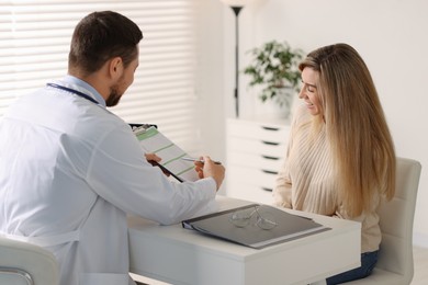 Professional doctor working with patient at white table in hospital