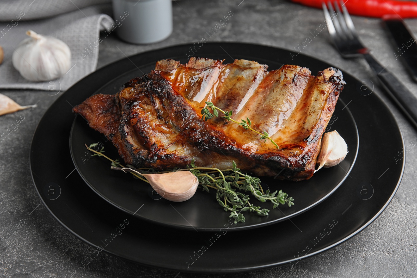 Photo of Tasty grilled ribs with thyme on grey table
