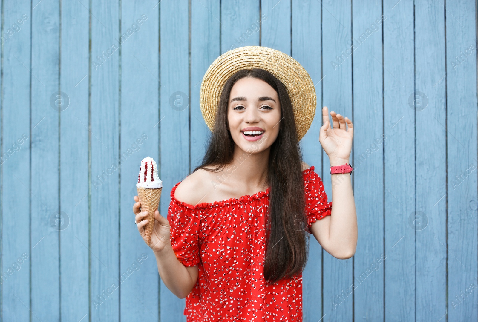 Photo of Happy young woman with delicious ice cream in waffle cone near wooden wall