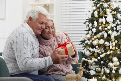 Happy mature couple with gift box at home. Christmas celebration