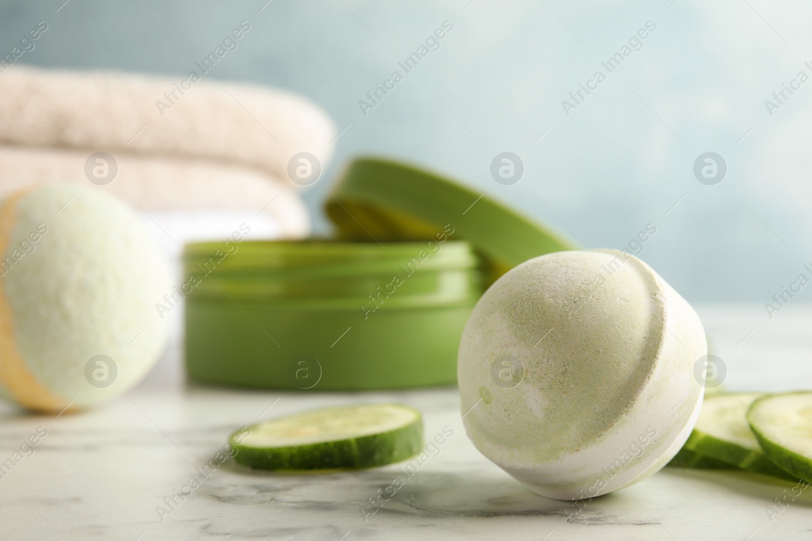 Photo of Bath bomb and cucumber slices on marble table. Space for text