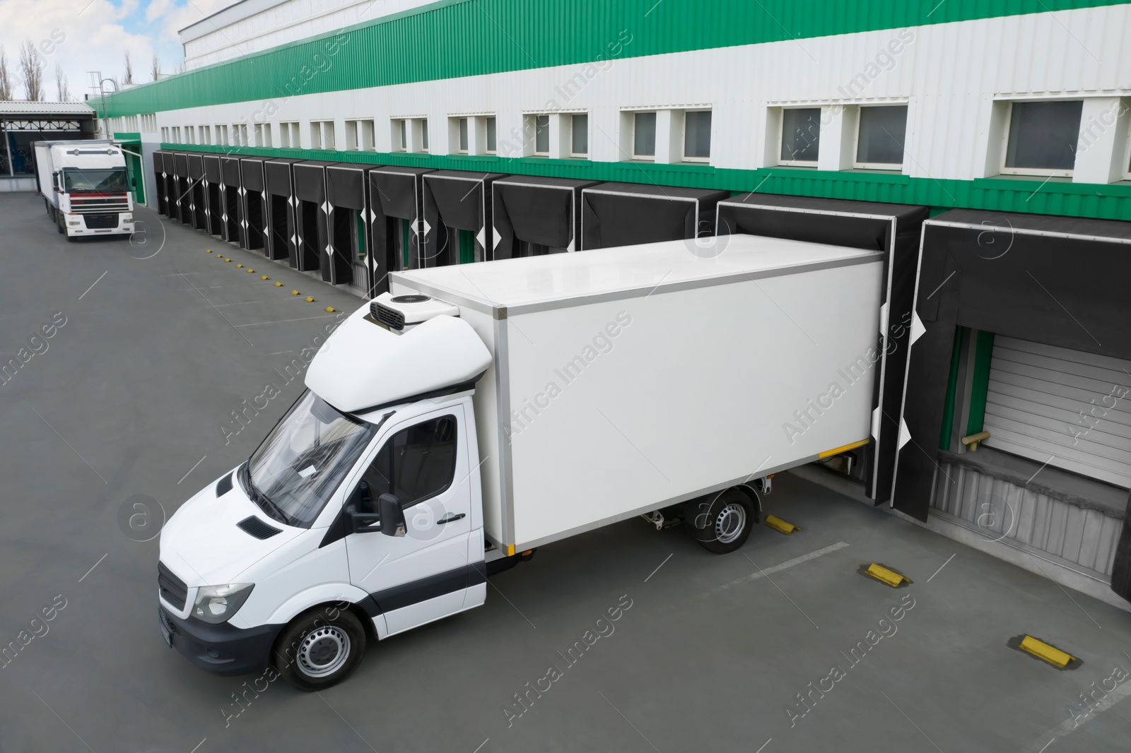 Image of Trucks near big warehouse outdoors. Logistics center