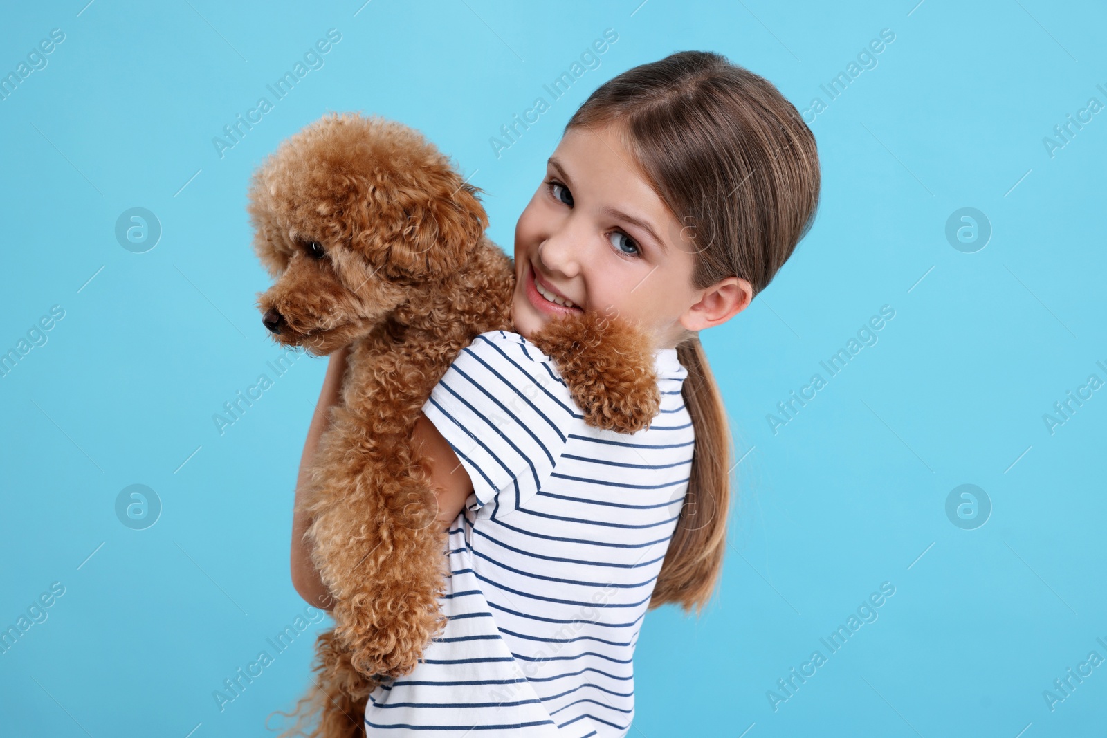 Photo of Little child with cute puppy on light blue background. Lovely pet