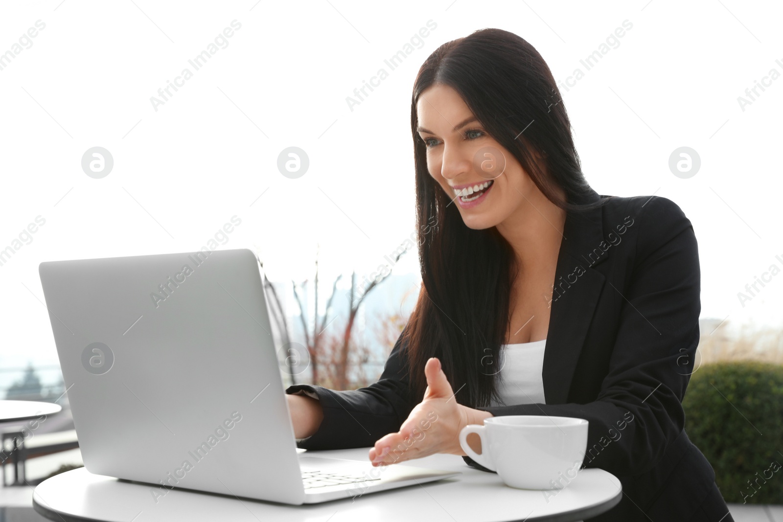 Photo of Emotional businesswoman working with laptop in outdoor cafe. Corporate blog