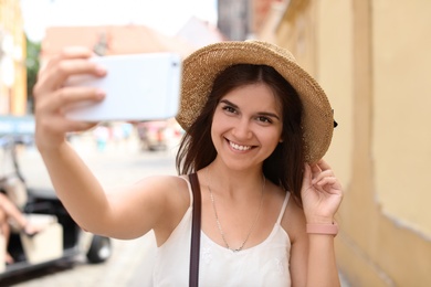 Photo of Young woman taking selfie on city street