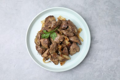 Tasty fried chicken liver with onion and parsley on grey table, top view