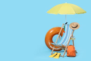 Photo of Deck chair, backpack and beach accessories on light blue background, space for text