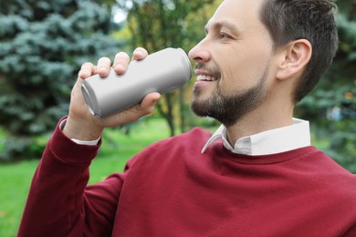 Happy man drinking from tin can in park, closeup