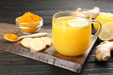 Photo of Immunity boosting drink with ginger, lemon and turmeric on dark wooden table