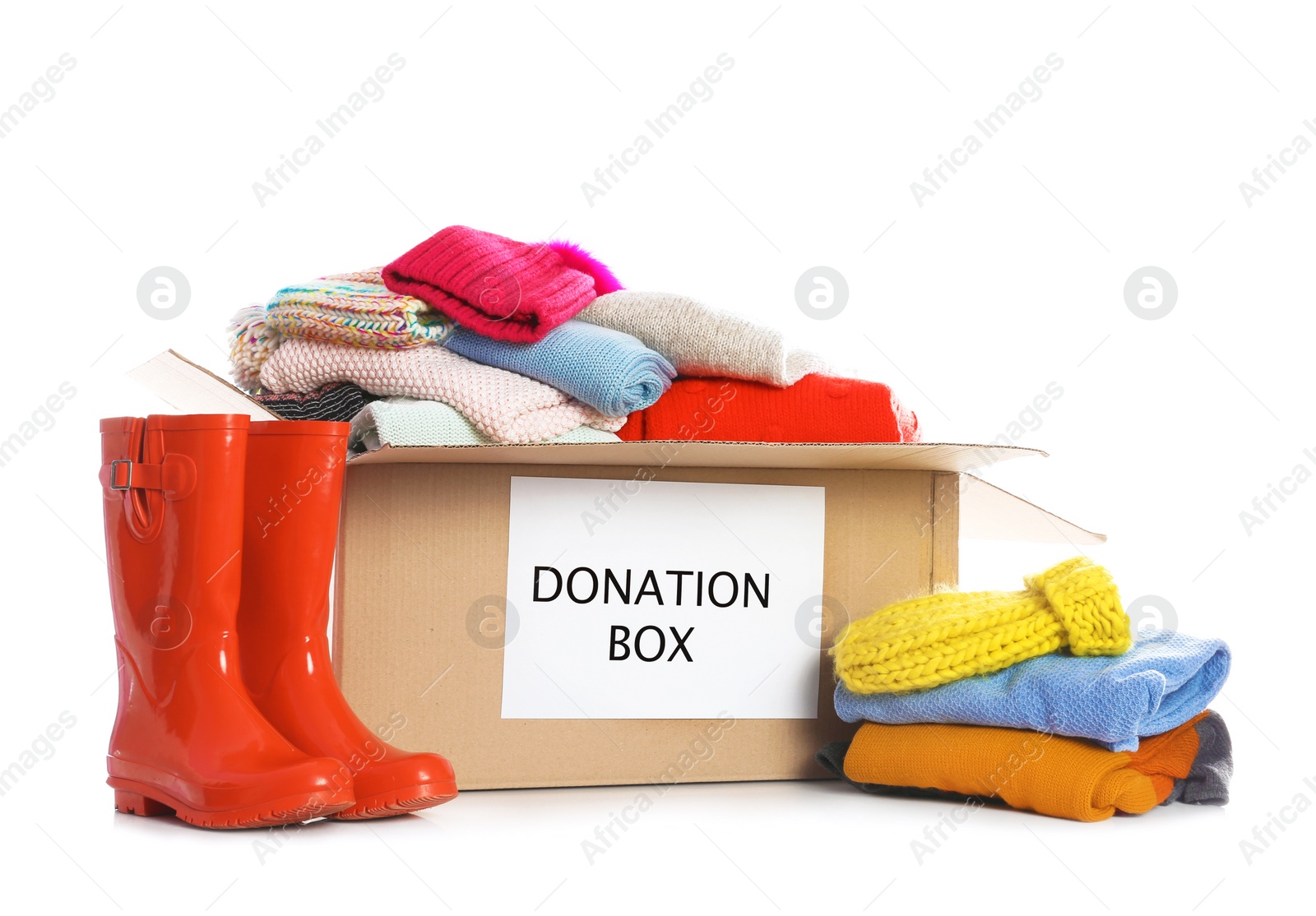 Photo of Donation box, rubber boots and clothes on white background