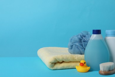Baby cosmetic products, bath duck, accessories and towel on light blue background. Space for text