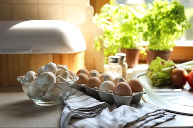 Fresh mushrooms and carton of eggs on table in kitchen