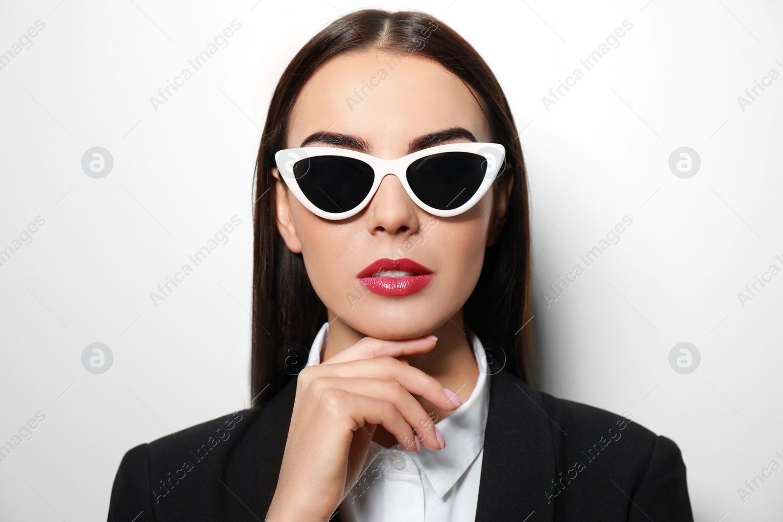 Photo of Young businesswoman in stylish sunglasses on light background