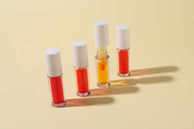 Photo of Many bright lip glosses on beige background