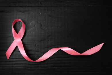 Photo of Pink ribbon on wooden background, top view with space for text. Breast cancer concept