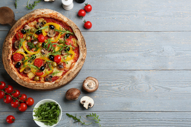 Flat lay composition with vegetable pizza on light grey wooden table. Space for text