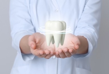 Image of Dentist demonstrating virtual model of healthy tooth on light background, closeup