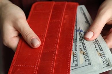 Photo of Money exchange. Woman putting dollar banknotes into wallet, closeup view
