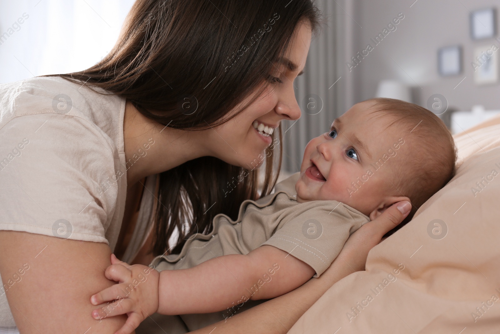 Photo of Happy young mother with her cute baby at home, closeup