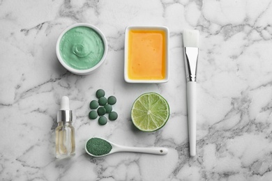 Flat lay composition with spirulina facial mask and ingredients on marble table