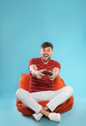 Emotional man playing video games with controller on color background. Space for text