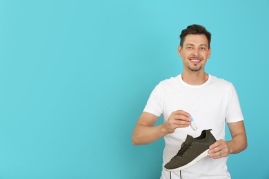 Man putting capsule shoe freshener in footwear on color background