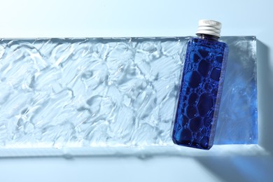 Photo of Bottle of cosmetic product on light blue background, top view