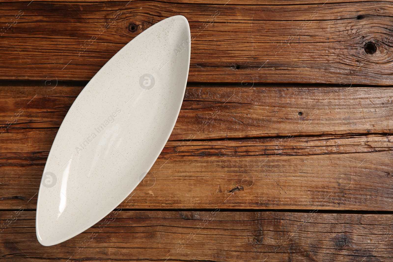 Photo of One ceramic plate on wooden table, top view. Space for text