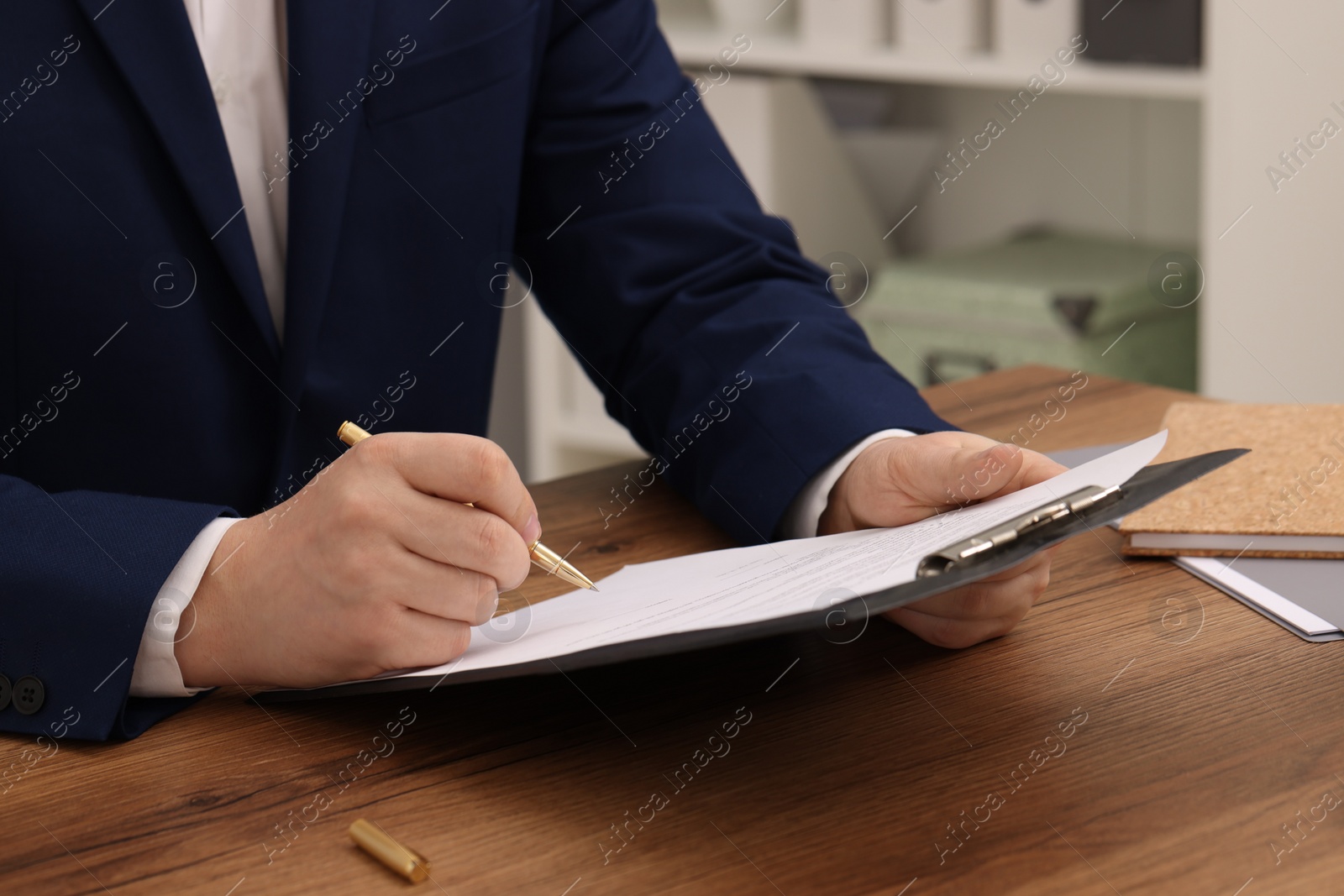 Photo of Man signing document at wooden table, closeup