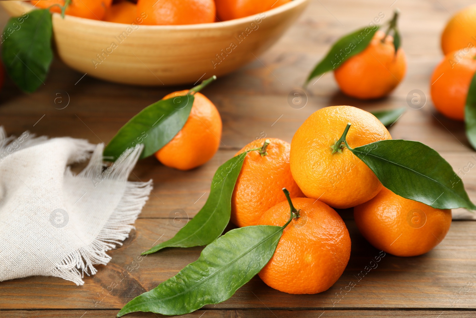 Photo of Fresh ripe tangerines with green leaves on wooden table