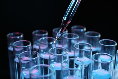 Photo of Dripping reagent into test tube on black background, closeup. Laboratory analysis